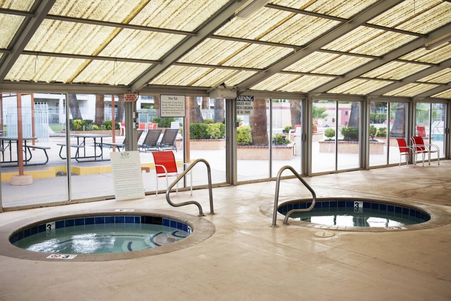 Uma área de piscina coberta com duas banheiras de hidromassagem, uma mesa para piquenique e assentos externos.