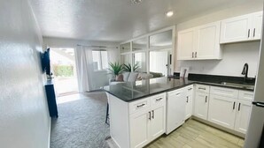 A modern kitchen with white cabinets, a black countertop, and a built-in stove. There is a large window providing natural light and a view of the outdoors. - Newly Renovated St. George Getaway!! (St. George)
