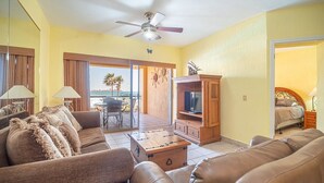 Ein Wohnzimmer mit einer Couch, einem Couchtisch, einer TV-Konsole und einem Balkon mit Meerblick.