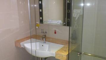 Uma casa de banho moderna com cabine de duche em vidro, uma pia com bancada de mármore e um espelho sobre a pia.