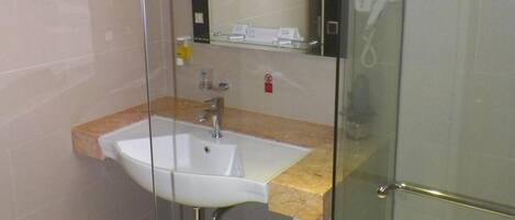 A modern bathroom with a glass shower enclosure, a sink with a marble countertop, and a mirror above the sink.