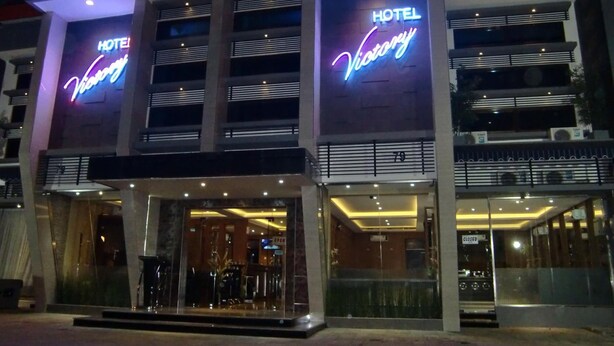 A hotel with a modern facade, illuminated signage, and a glass entrance. - Hotel Victory Bandung (Bandung)