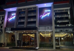 A hotel with a modern facade, illuminated signage, and a glass entrance. - Hotel Victory Bandung (Bandung)