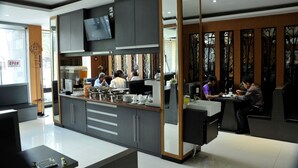 A modern restaurant with a central counter, seating area, and a TV mounted above the counter. - Hotel Victory Bandung (Bandung)