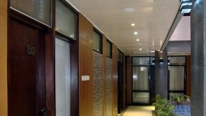 A modern hotel corridor with wooden paneling, a tiled floor, and recessed lighting. - Hotel Victory Bandung (Bandung)