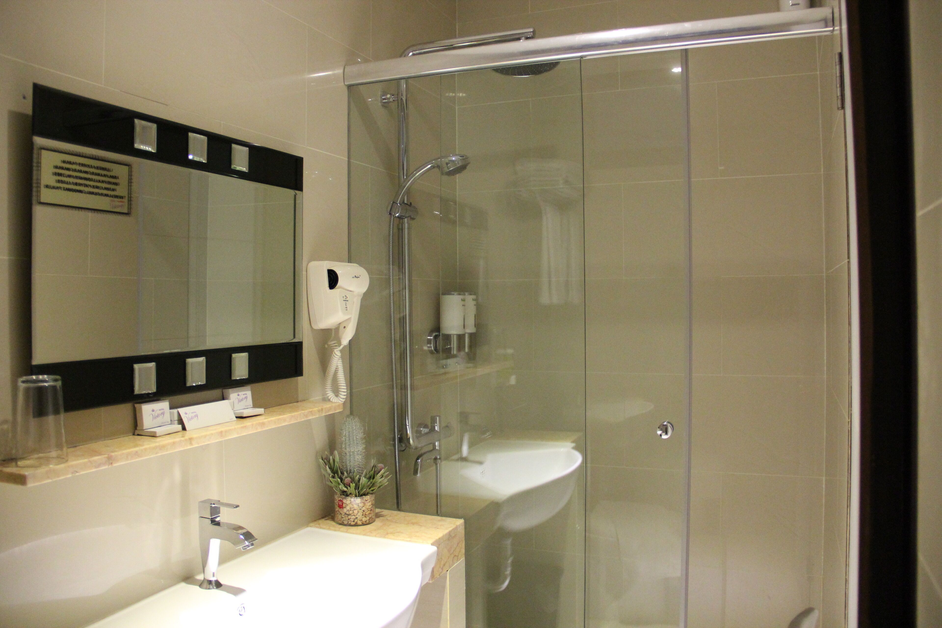 A modern bathroom with a glass-enclosed shower, a white sink, and a mirror above the sink.