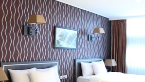 A hotel room with two beds, a large window, and a wavy-patterned wall. - Hotel Victory Bandung (Bandung)