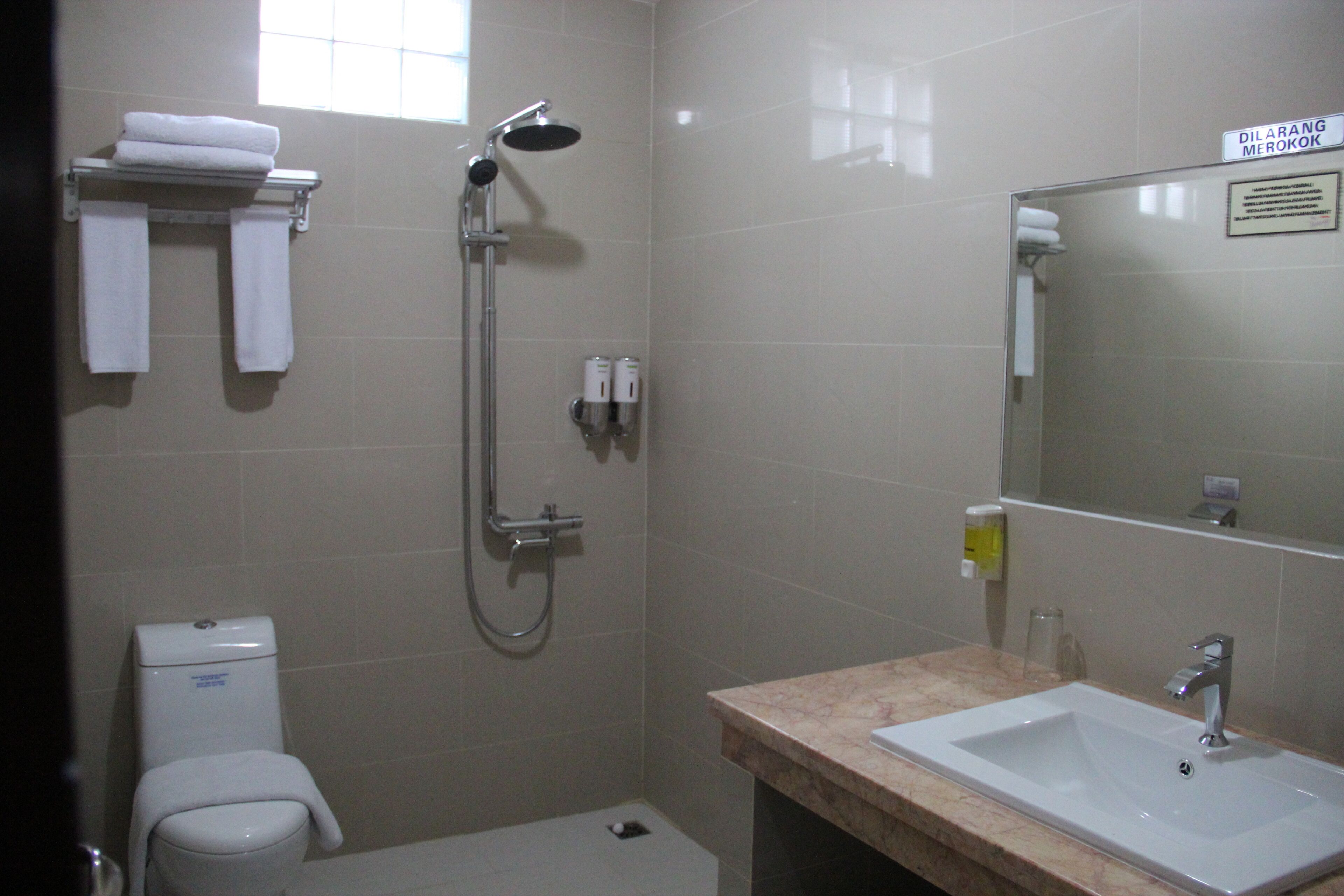 Un baño con ducha, inodoro, lavamanos y toallero con toallas.
