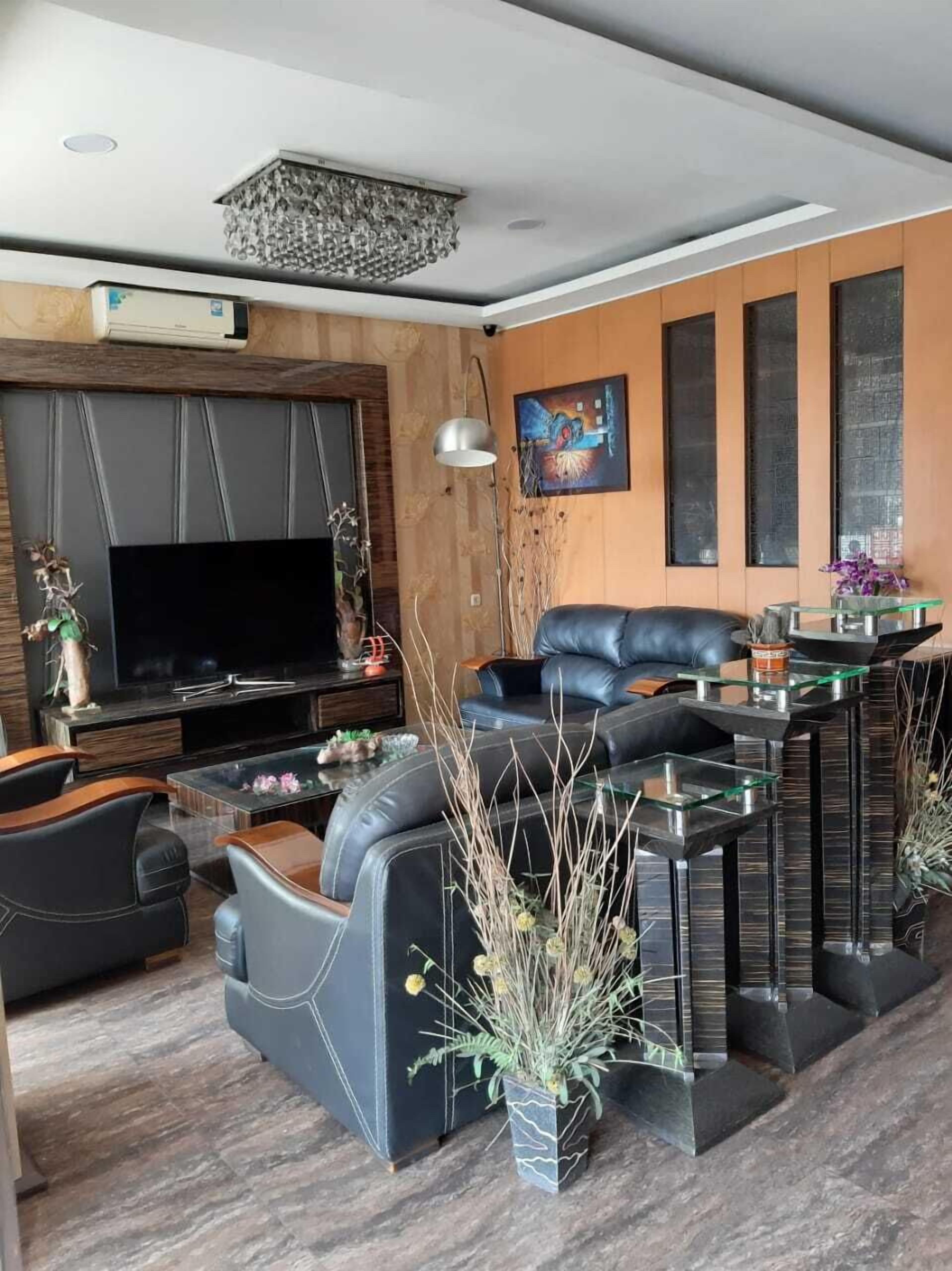 A modern living room with a flat-screen TV, leather sofa, and a glass coffee table.