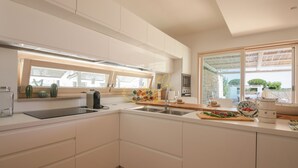 A modern kitchen with white cabinetry, a large window, and a view of the outdoors. - TD Villa Fico Jo Villa with Pool & Lush Garden (Conversano)