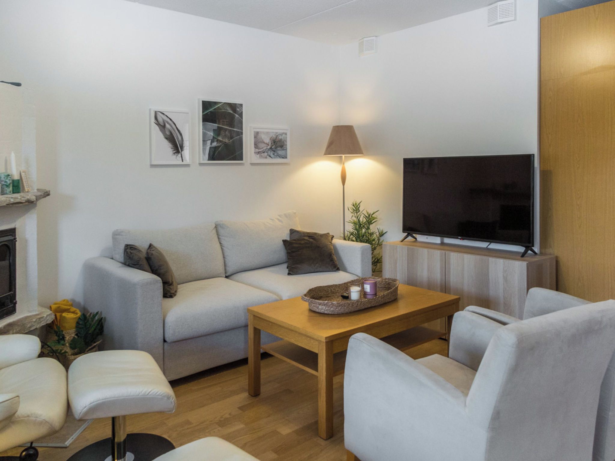 Een moderne woonkamer met een bank, fauteuils, een salontafel, een flatscreen-televisie en kunst aan de muur.