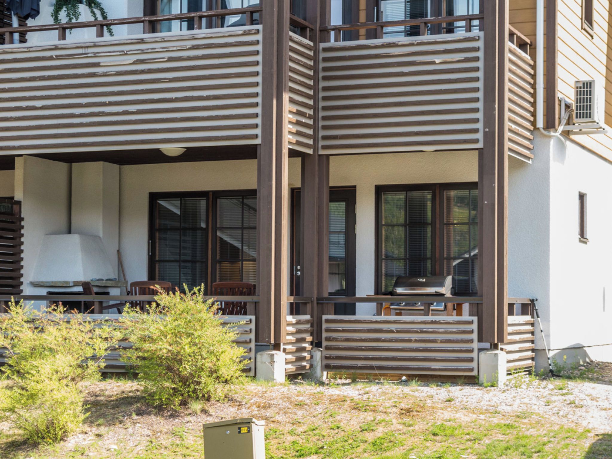 A modern two-story building with a balcony, large windows, and outdoor seating.
