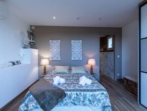 A bedroom with a bed, two wall-mounted lamps, decorative wall art, and a wooden bench.