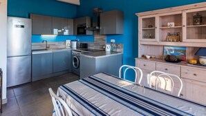 A compact kitchen with modern appliances, a dining area with a striped tablecloth, and a blue accent wall.