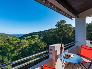 A balcony with a table and chairs, overlooking a mountainous landscape.