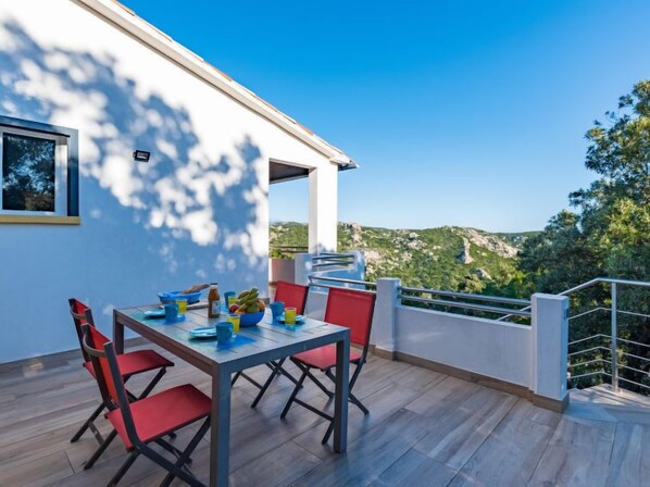 A dining area with a table and chairs, a window, and a view of a mountainous landscape.