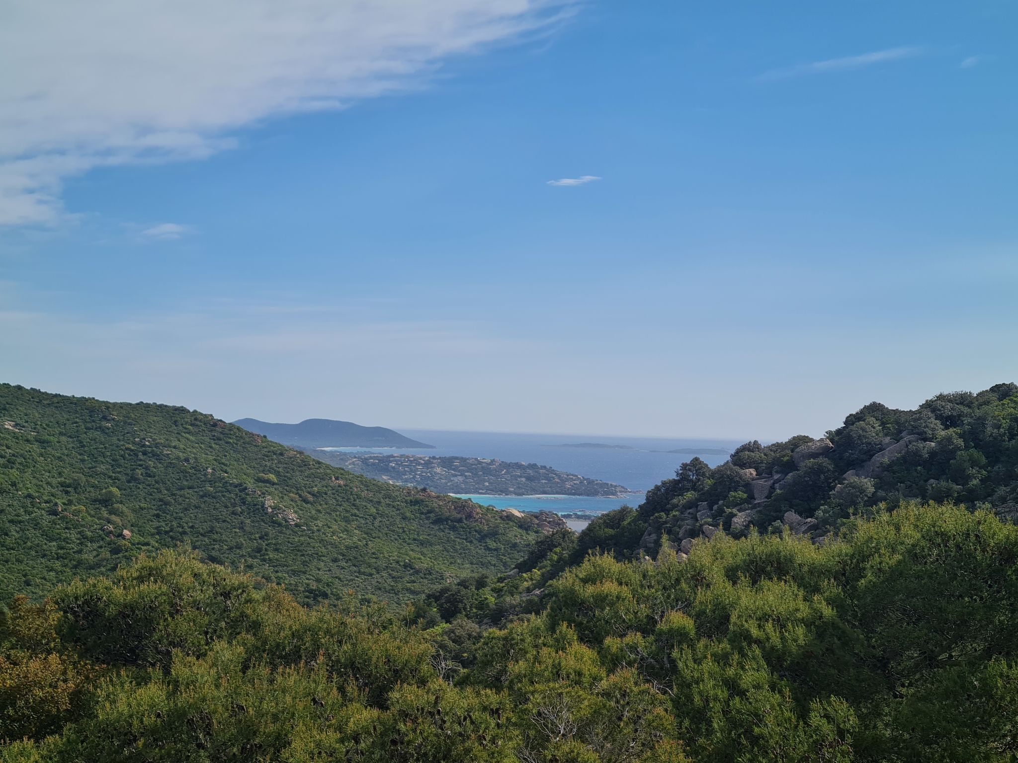 A mountainous landscape with dense green vegetation and a clear blue sky.