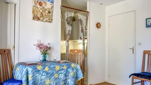 Un coin repas avec une table dressée pour deux personnes, un vase rempli de fleurs et une œuvre d’art murale.