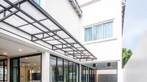 A modern indoor swimming pool with glass walls and a patio area. - Pool Villa Pattaya - Exquisite Pool Villa H (Pattaya City)