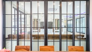 A modern interior with a sliding glass partition, wooden furniture, and a view of a spacious area with seating and a ceiling light fixture. - Pool Villa Pattaya - Exquisite Pool Villa H (Pattaya City)