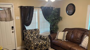A living room with a ceiling fan, a brown leather couch, patterned armchair, and a zebra-striped ottoman. - My Lil Red House.... (Baton Rouge)