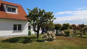 Uma casa com telhado vermelho, uma janela pequena e uma árvore no quintal.