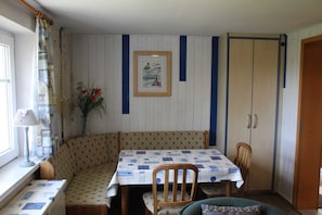 Un comedor con una mesa lista para dos, una banca y un armario.