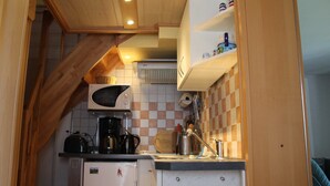 Een kleine keuken met een magnetron, koffiezetapparaat en een koelkastje.