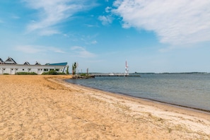 A beach with a row of houses, a pier, and a lighthouse.