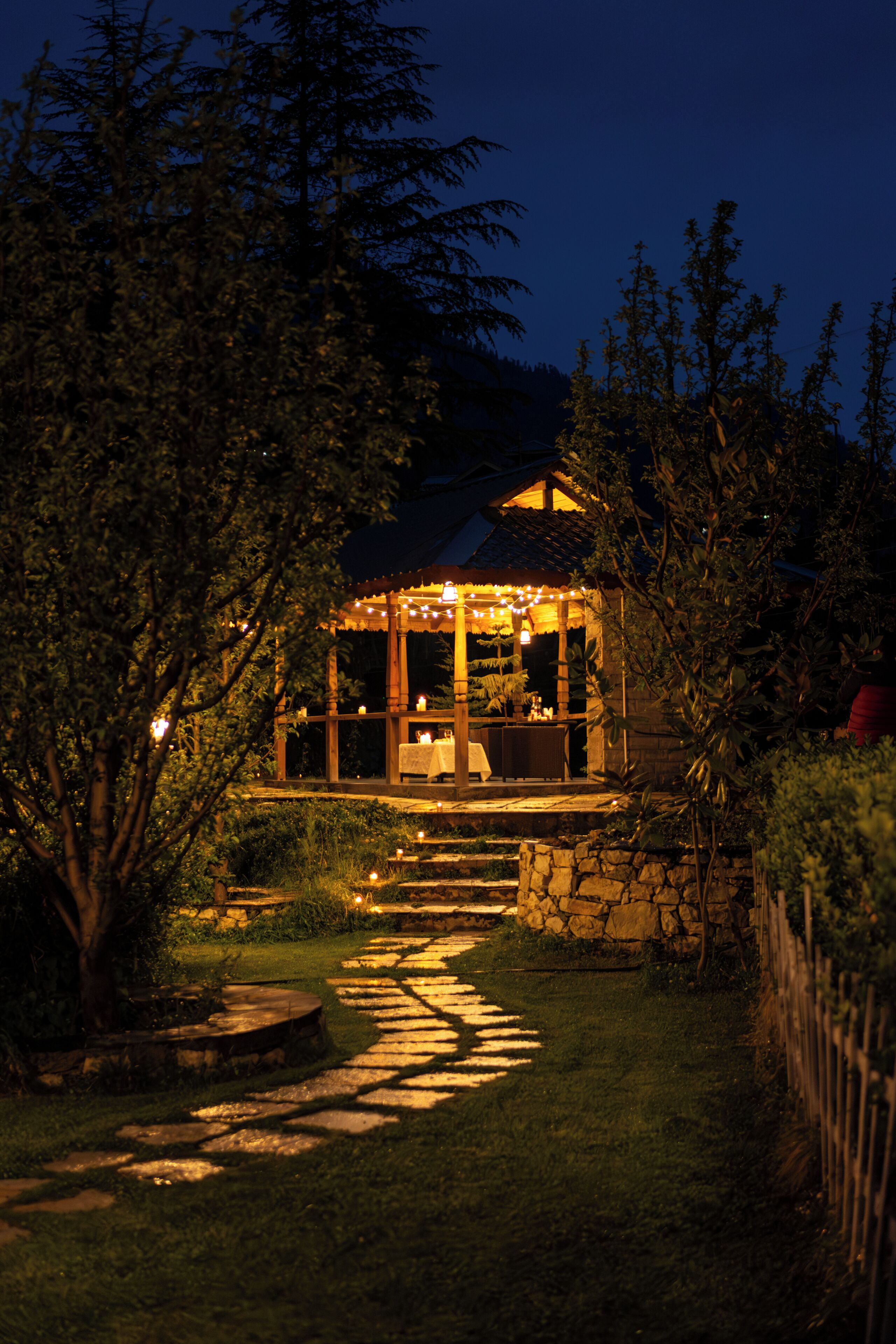 A gazebo with a stone pathway leading to it, surrounded by greenery.