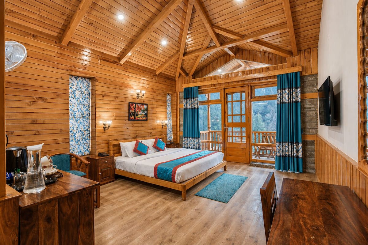 A wooden cabin with a bed, a dining table, and a TV.