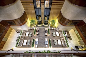 A spacious lobby with multiple seating areas, a central staircase, and a decorative ceiling.