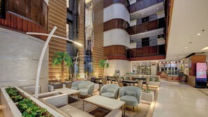 En moderne hotellobby med et centralt siddeområde, flere etager og en restaurant.