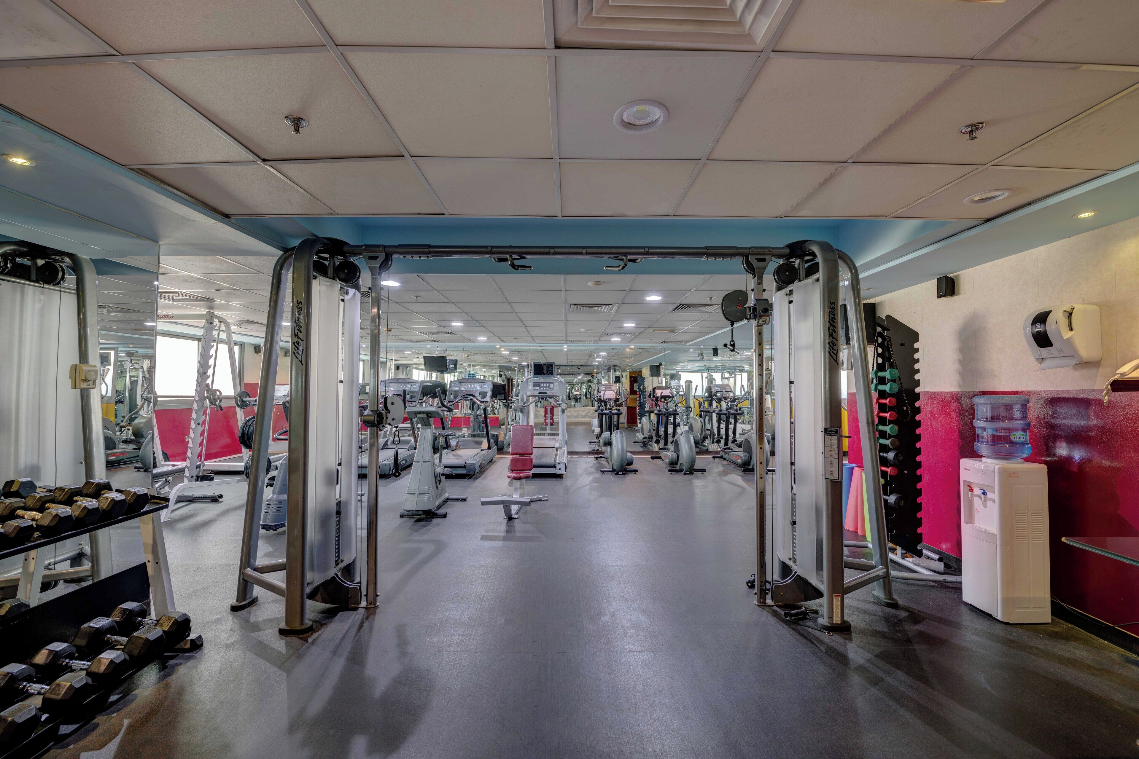 Ett gym med olika typer av träningsutrustning, inklusive hantlar, löpband och styrketräningsmaskiner.