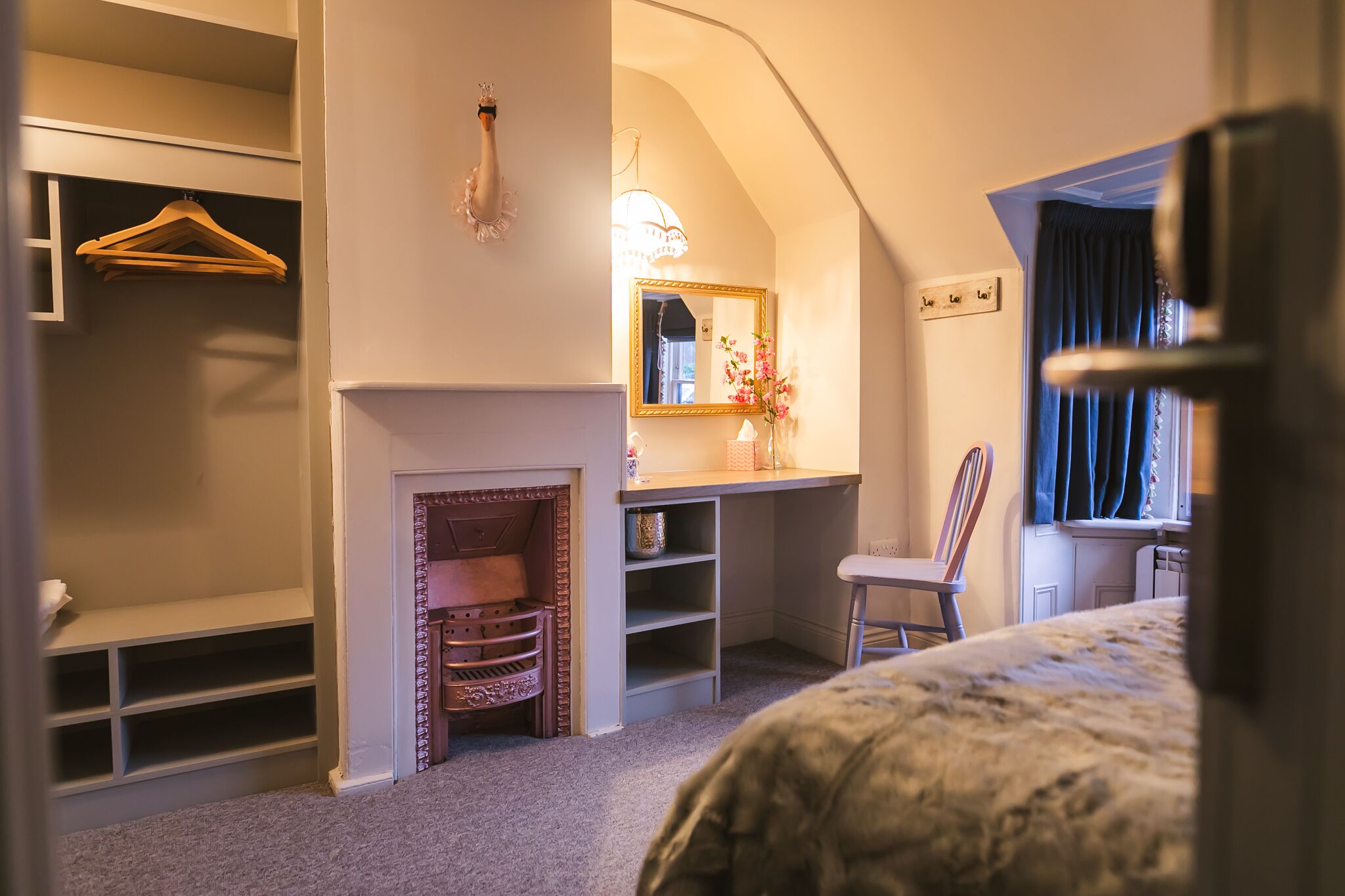 A bedroom with a bed, a dresser, a mirror, a chair, and a fireplace.