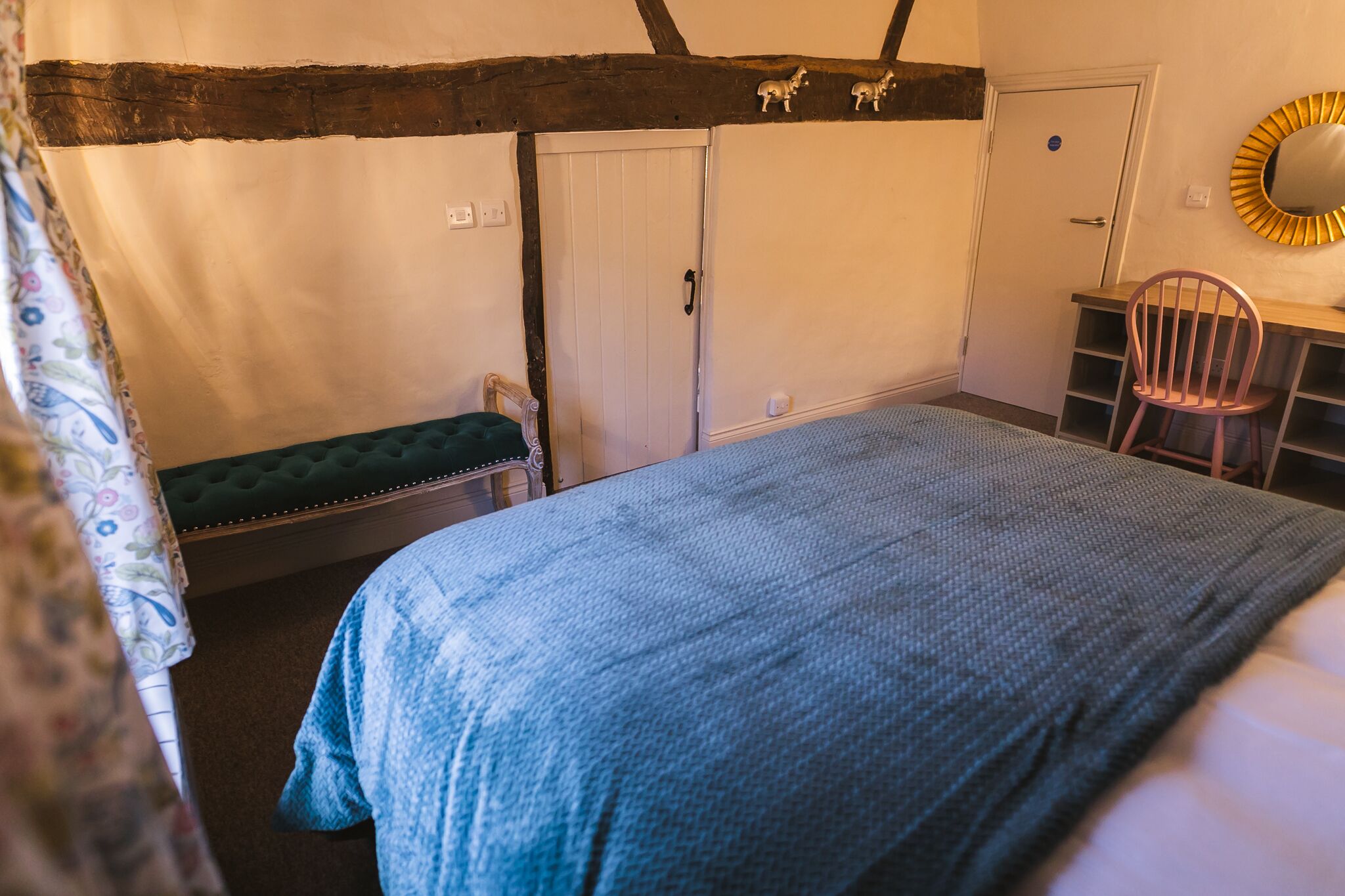 A bedroom with a bed, a bench, a desk, and a chair.