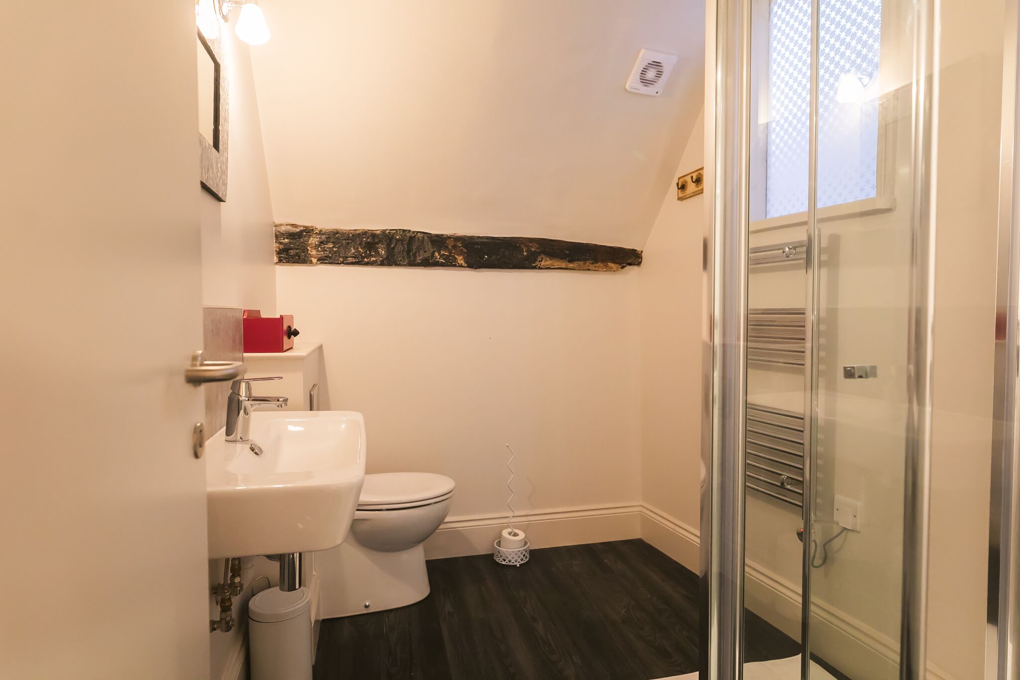 A bathroom with a white sink, toilet, and glass shower enclosure.