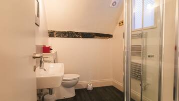 A bathroom with a white sink, toilet, and glass shower enclosure.