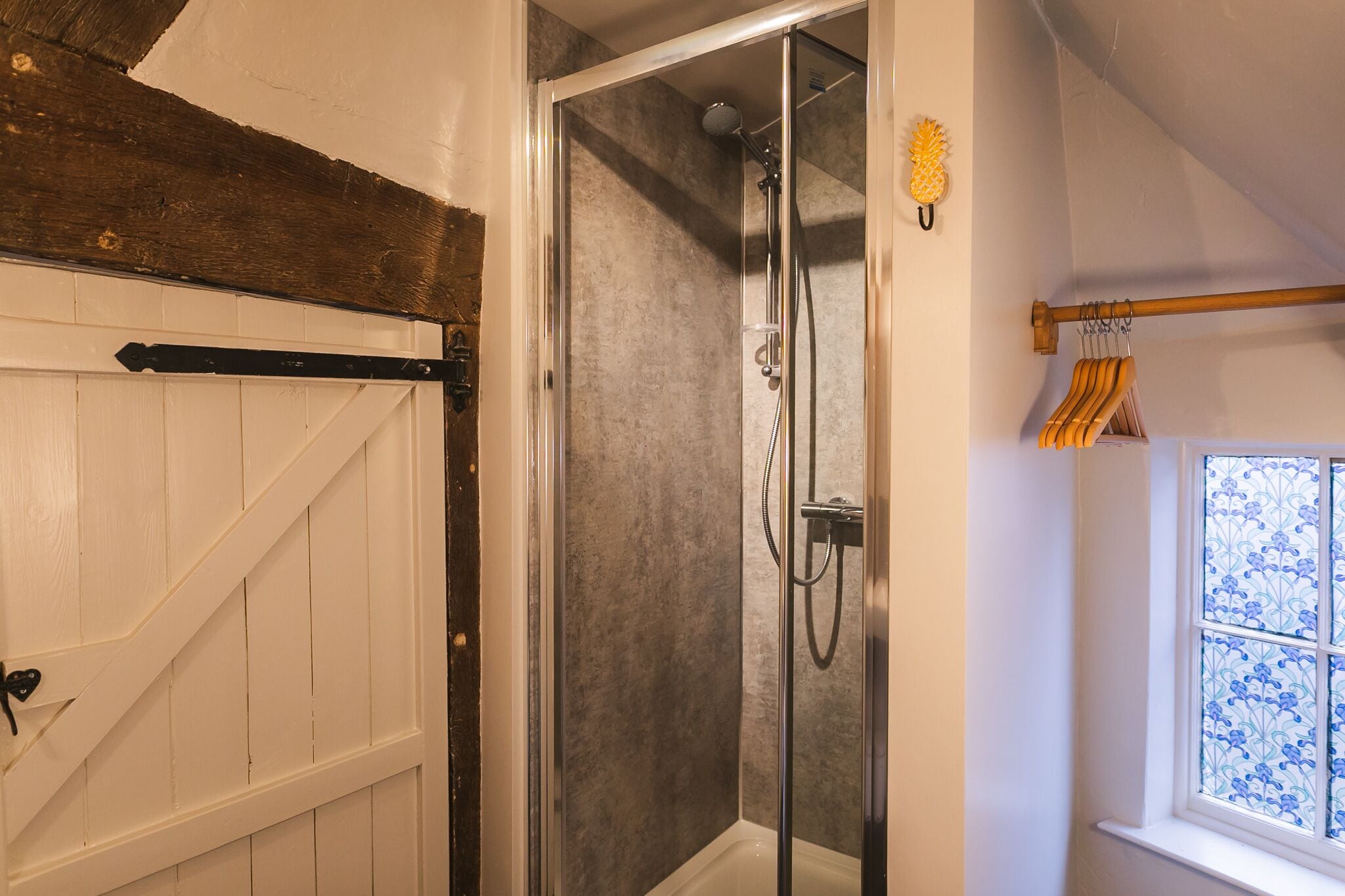 A glass-enclosed shower with a handheld showerhead and a wall-mounted faucet.