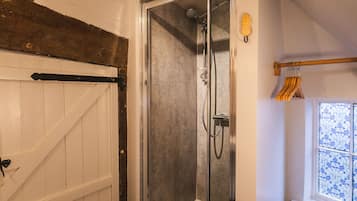 A glass-enclosed shower with a handheld showerhead and a wall-mounted faucet.