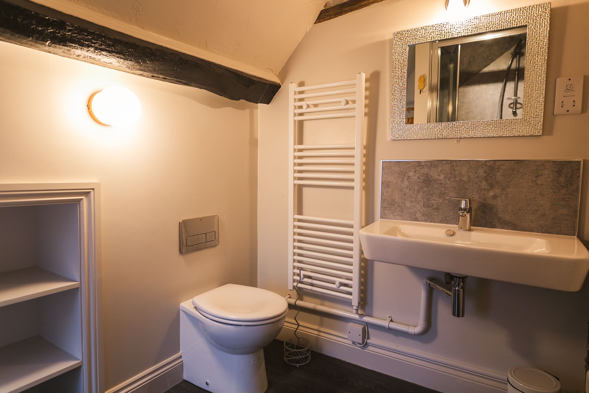 Een badkamer met toilet, een witte wastafel, een spiegel en een handdoekrek.
