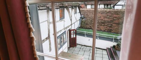 A view through a window of a traditional half-timbered building with a wooden bench and a small table outside.