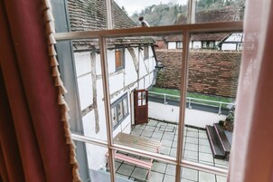 Vista desde una ventana de un edificio tradicional de entramado de madera con un banco y una mesa pequeña afuera.