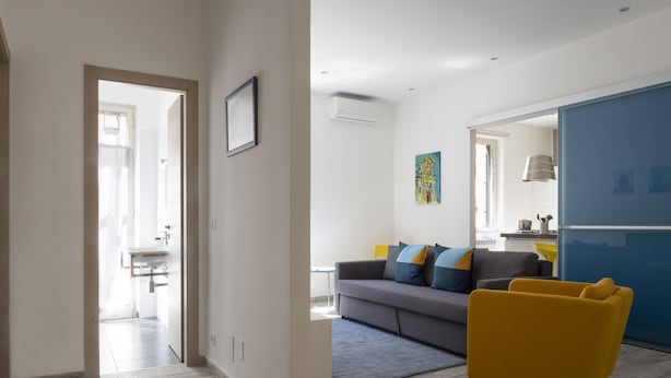Una sala de estar moderna con un sofá, un sillón amarillo y una pared de acento azul.