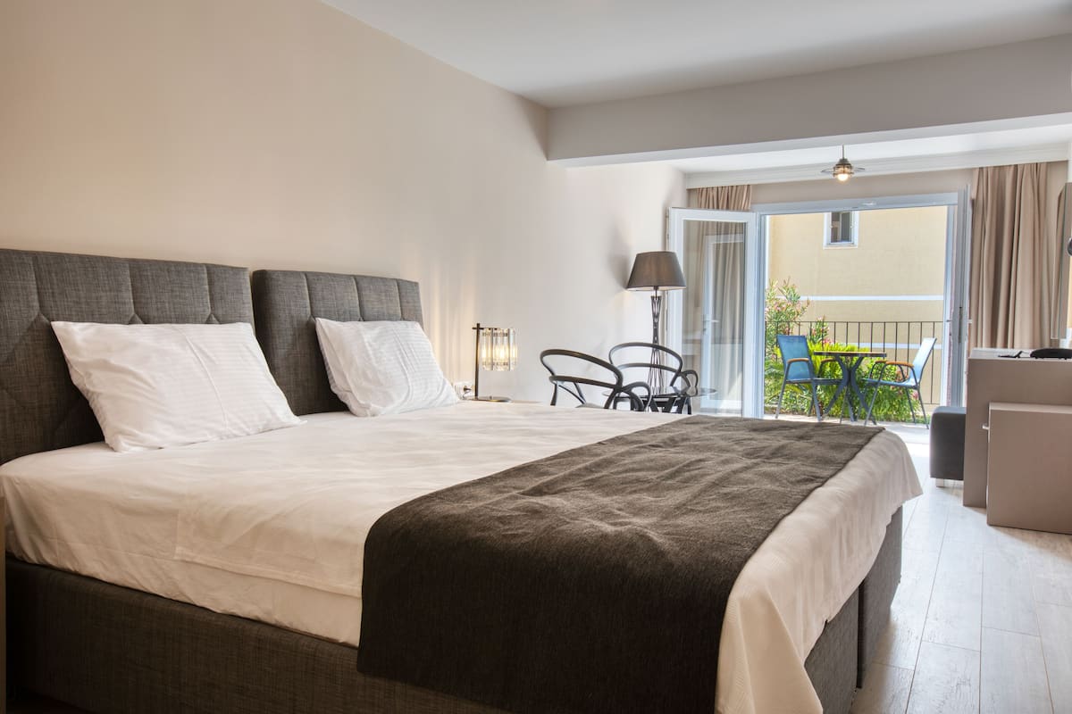 Ein Hotelzimmer mit einem großen Bett, einem Schreibtisch und einem Balkon mit Stühlen.