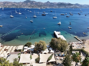 A coastal area with numerous boats, clear water, and a beach with umbrellas and outdoor seating. - Farrys Boutique Hotel & Beach Club (Bodrum)