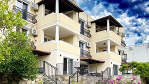 A multi-story residential building with balconies, stone walls, and a garden with flowers. - Farrys Boutique Hotel & Beach Club (Bodrum)