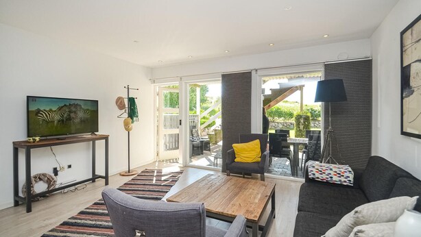 A modern living room with a flat-screen TV, a wooden coffee table, and a grey sofa.