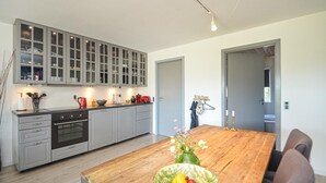 A modern kitchen with grey cabinets, a wooden dining table, and a vase of flowers.