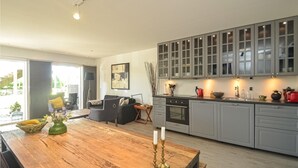 A modern kitchen with grey cabinets, a wooden dining table, and a view of the outdoors.